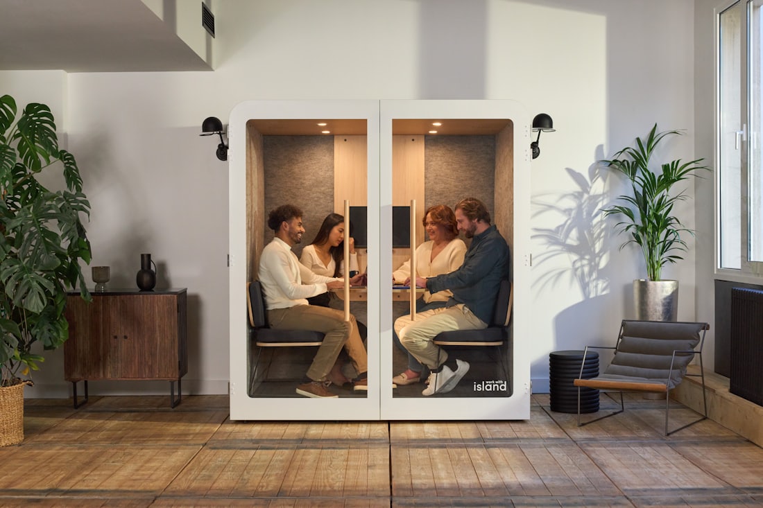 Four colleagues seated around a table in a large acoustic meeting pod